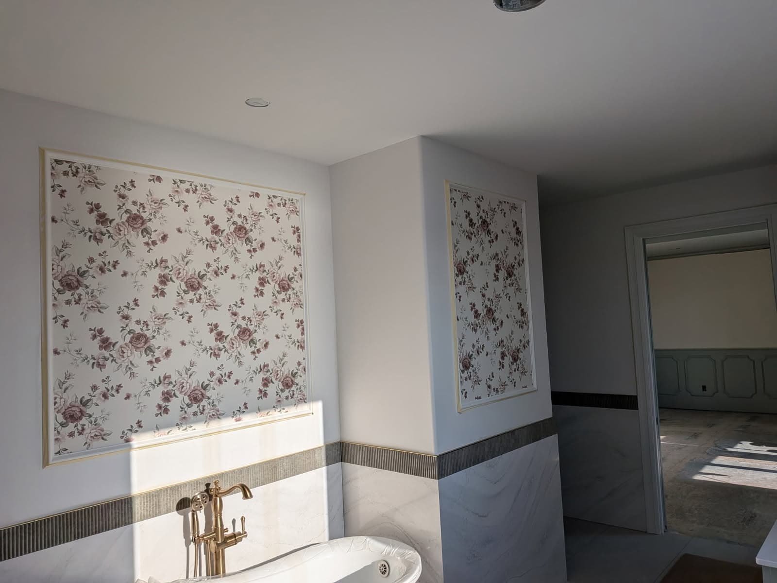 Framed floral wallpaper panels in a marble primary bathroom